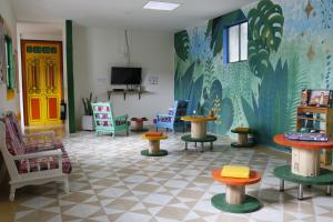 a room with colorful chairs and tables and a mural at Golden Frog Manizales in Manizales