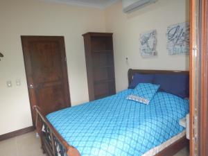 1 dormitorio con 1 cama con edredón azul en Macaws Ocean Club Apartamento # 18, en Jacó