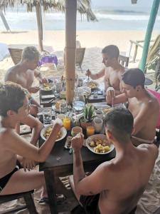 un grupo de chicos comiendo en una mesa en la playa en La Máxima & LGBT en Zipolite