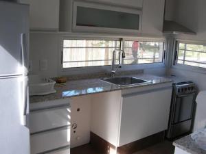 a kitchen with white cabinets and a sink and two windows at Sabiá in Cuchilla Alta