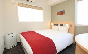 a bedroom with a large white bed with a red blanket at Urban Hotel Kyoto Nijo Premium in Kyoto