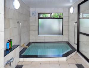 ein Bad mit einem Pool und einem Fenster in der Unterkunft Ryokan Seifuso in Matsumoto