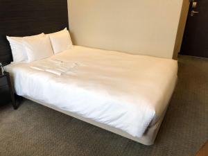 a large bed with white sheets and pillows at Citadines Central Shinjuku Tokyo in Tokyo