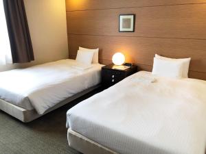 a hotel room with two beds and a lamp at Citadines Central Shinjuku Tokyo in Tokyo
