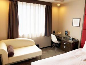 a hotel room with a couch and a desk and a deskablish at Citadines Central Shinjuku Tokyo in Tokyo