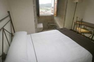 a white bed in a room with a window at Hospedería San Martín Pinario in Santiago de Compostela
