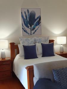 um quarto com uma cama com almofadas azuis e brancas em The Paddocks em Maleny