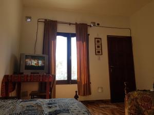 Schlafzimmer mit einem Bett, einem TV und einem Fenster in der Unterkunft Hostel Casa de Familia in Humahuaca