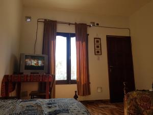 a bedroom with a bed and a television and a window at Hostel Casa de Familia in Humahuaca