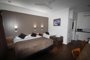 ein Hotelzimmer mit 2 Betten und einem Tisch in der Unterkunft Colonial Rose Motel in Townsville