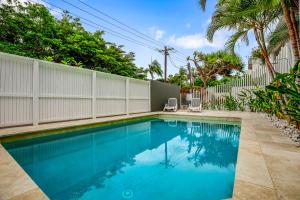 a swimming pool with two chairs next to a fence at Seascape in Sunshine Beach