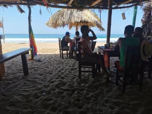 un grupo de personas sentadas en mesas en la playa en La Máxima & LGBT en Zipolite
