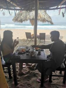 dos personas sentadas en una mesa en la playa en La Máxima & LGBT en Zipolite