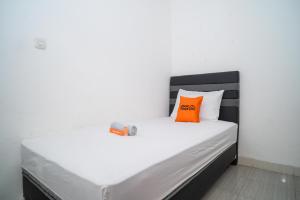a white bed with an orange pillow on it at KoolKost Syariah near Stasiun Rawa Buntu (Minimum Stay 6 Nights) in Tangerang