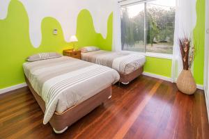 two beds in a room with green walls and wooden floors at Swell Shack in Dunsborough