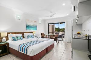 Blue Lagoon Resort في شاطئ ترينيتي: غرفة نوم بسرير ومطبخ مع طاولة