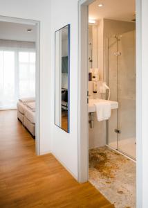 łazienka z prysznicem, umywalką i łóżkiem w obiekcie HAIMHAUSERS Hotel Garni w mieście Haimhausen