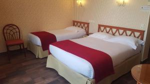 two beds in a hotel room with a table and chairs at Hôtel de Charme Brise Marine in Saint-Jean-Cap-Ferrat