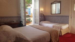 two beds in a room with a window at Hôtel de Charme Brise Marine in Saint-Jean-Cap-Ferrat