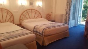 a hotel room with two beds and a window at Hôtel de Charme Brise Marine in Saint-Jean-Cap-Ferrat
