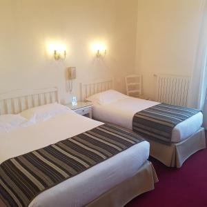 a hotel room with two beds and two chairs at Hôtel de Charme Brise Marine in Saint-Jean-Cap-Ferrat