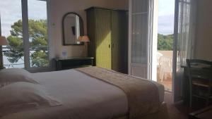 a bedroom with a bed and a view of a balcony at Hôtel de Charme Brise Marine in Saint-Jean-Cap-Ferrat