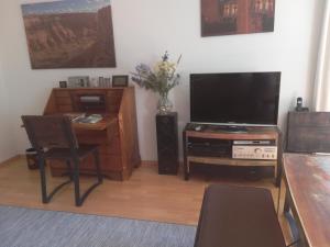 ein Wohnzimmer mit einem TV und einem Schreibtisch mit einem Tisch in der Unterkunft Ferienwohnung am Kunstberg 29 in Altenau