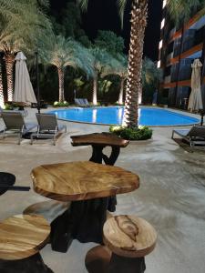 patio ze stołami i krzesłami przed basenem w obiekcie APARTMENTS MBC w mieście Mai Khao Beach