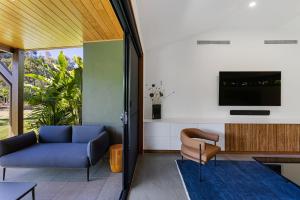 a living room with a couch and a tv at Aqua - at Funnel bay in Airlie Beach