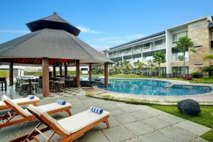 a resort pool with chairs and a gazebo at Swiss-Belhotel Borneo Banjarmasin in Banjarmasin