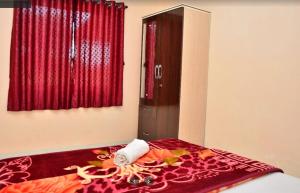 Schlafzimmer mit einem Bett mit einem roten Vorhang und einem Spiegel in der Unterkunft Savitri bungalow 3BHK in Panchgani