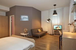 - une chambre avec un lit, un canapé et une télévision dans l'établissement Les Chambres du CTN, à Genève