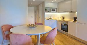 a kitchen with a table and pink chairs in a room at Victory Village 18E in Quinta do Lago
