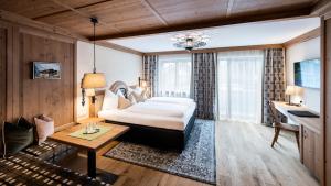 マイヤーホーフェンにあるAlpenhotel Kramerwirtのベッドとテーブルが備わるホテルルームです。