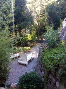 un jardin avec deux chaises blanches et des plantes dans l'établissement le vallon de bargemon, à Bargemon