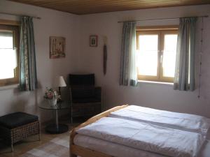 a bedroom with a bed and a chair and windows at Haus Hörger in Maierhöfen