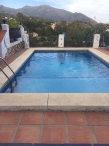 a large swimming pool with blue water and mountains in the background at Cute Little Casita in Mijas