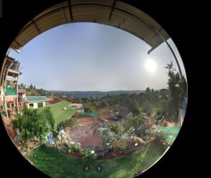 a view of a garden through a circular window at Krishan Kunj 6BHK in Mahabaleshwar