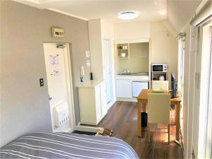 Una pequeña habitación con una cama y una cocina. en Hotel Peace Park Tokaichi, en Hiroshima