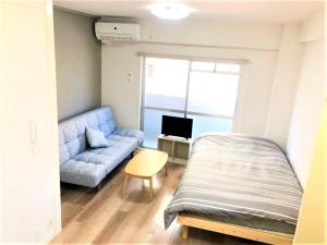 Un dormitorio con una cama y un sofá y una ventana. en Hotel Peace Park Tokaichi, en Hiroshima