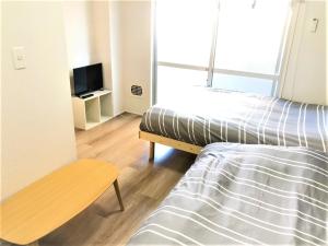 1 dormitorio con 1 cama, 1 silla y TV en Hotel Peace Park Tokaichi, en Hiroshima