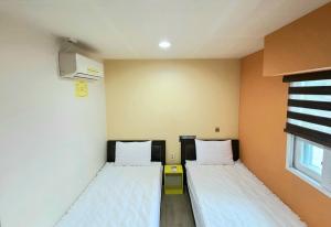 2 Betten in einem kleinen Zimmer mit Fenster in der Unterkunft Hostel Tommy in Seoul