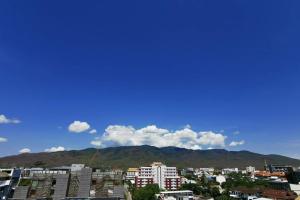 una ciudad con edificios y montañas en el fondo en Stay Nimmanhemin Center with Rooftop Pool 309NM, en Chiang Mai