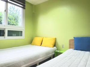 Duas camas num quarto com almofadas amarelas e azuis em Hostel Tommy em Seul