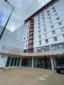 un grand bâtiment avec une voiture garée devant lui dans l'établissement Moov'Appart Hotel Clichy, à Clichy