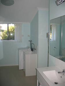 a white bathroom with a sink and a mirror at Paradise on The Boulevard - Beach Holiday Home 