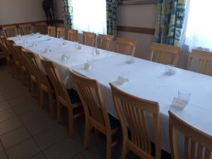 a long white table and chairs in a room at Vadaspuszta Vendeghaz in Csatka
