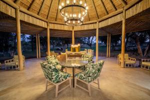 a patio with a table and chairs and a chandelier at Simbavati Camp George in Klaserie Private Nature Reserve