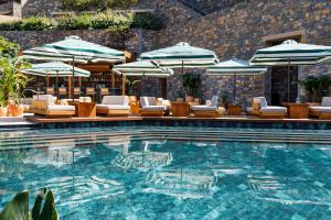 a swimming pool with chairs and umbrellas at Daios Cove in Agios Nikolaos
