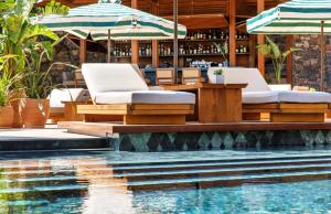 a swimming pool with two lounge chairs and a bar at Daios Cove in Agios Nikolaos